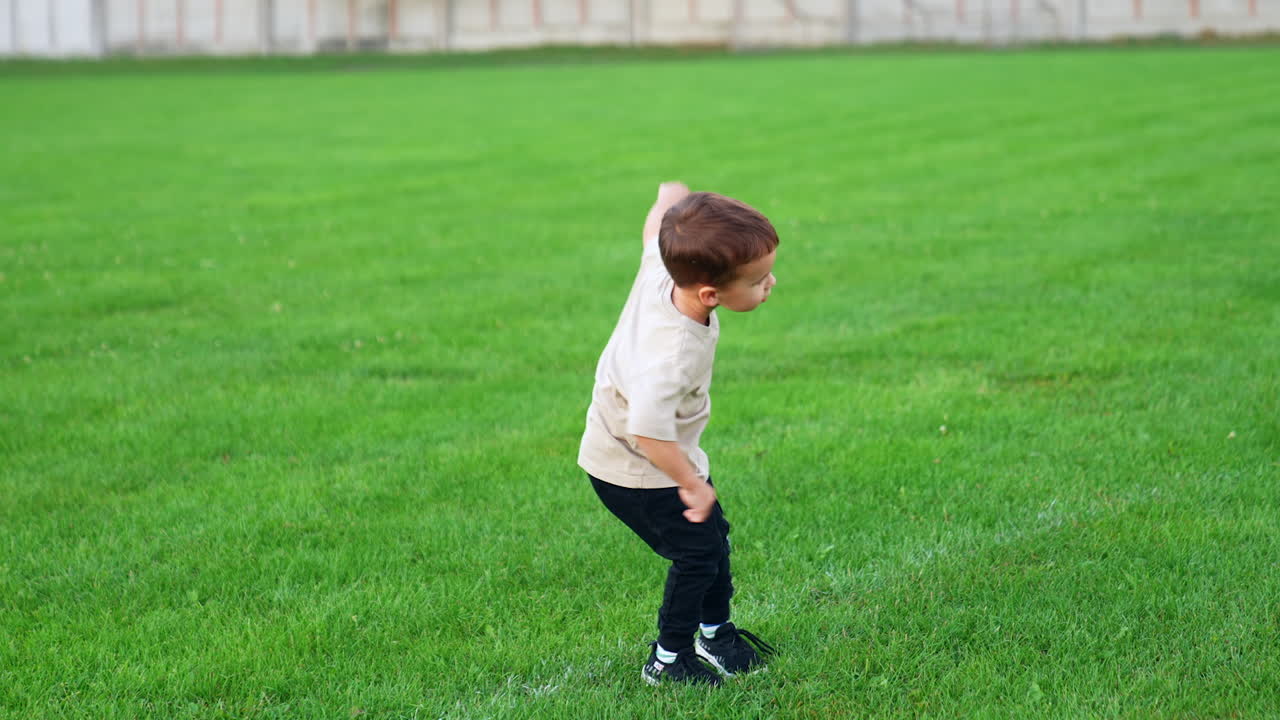 Lovely baby boy plays outdoors on the green lawn. Active time-spending in game in summer.
