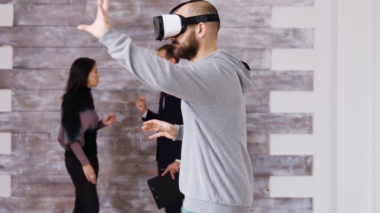 Uomo che usa un visore per realtà virtuale in ufficio con colleghi sullo sfondo