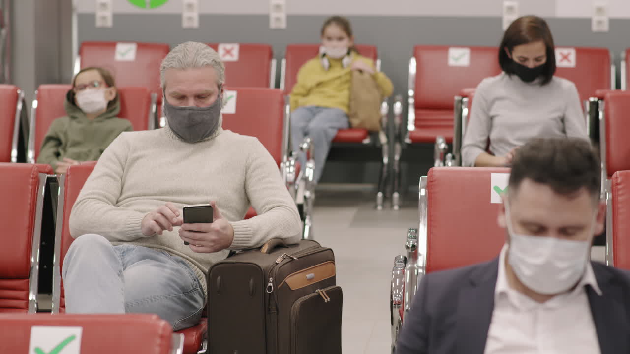 People With Smartphones In Departure Lounge