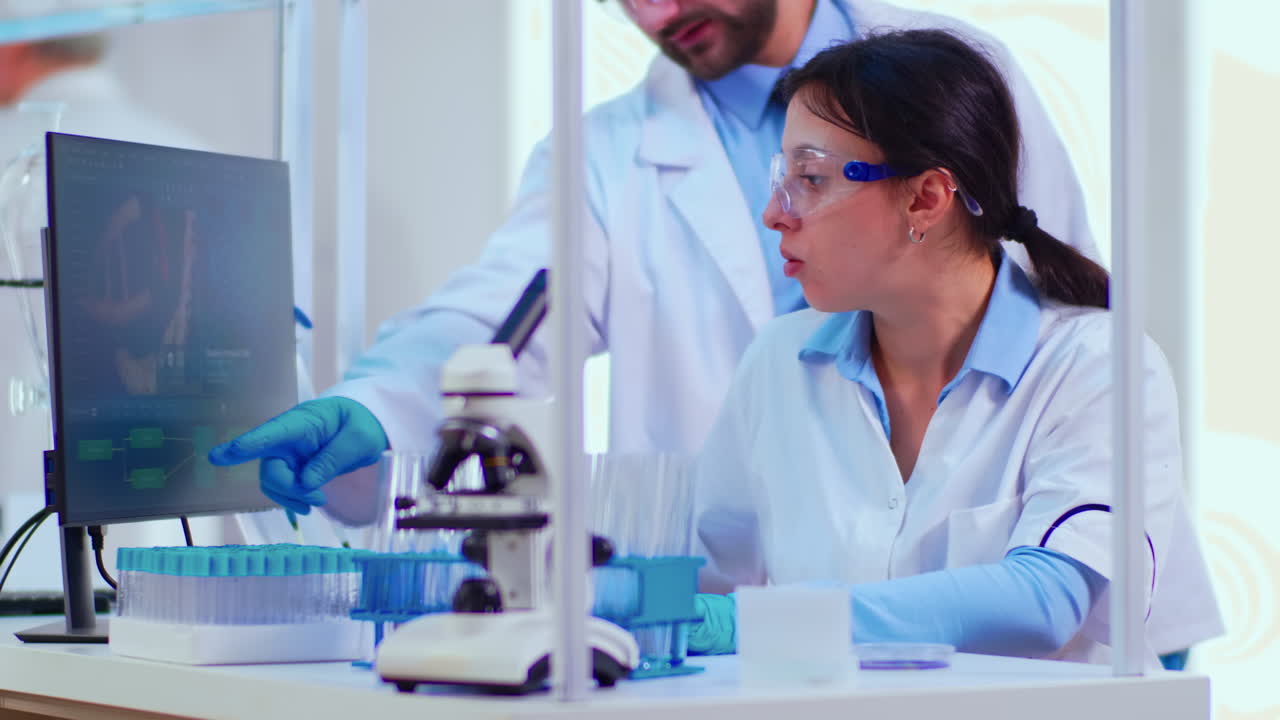 Biochemist writing on computer the changes in vaccine composition