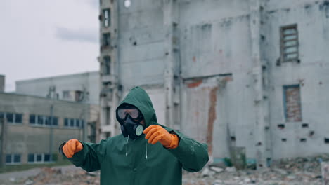 Human survivor standing alone in ruined place. Guy in the gas mask and safety clothes against the background of abandoned building. Apocalypse concept.