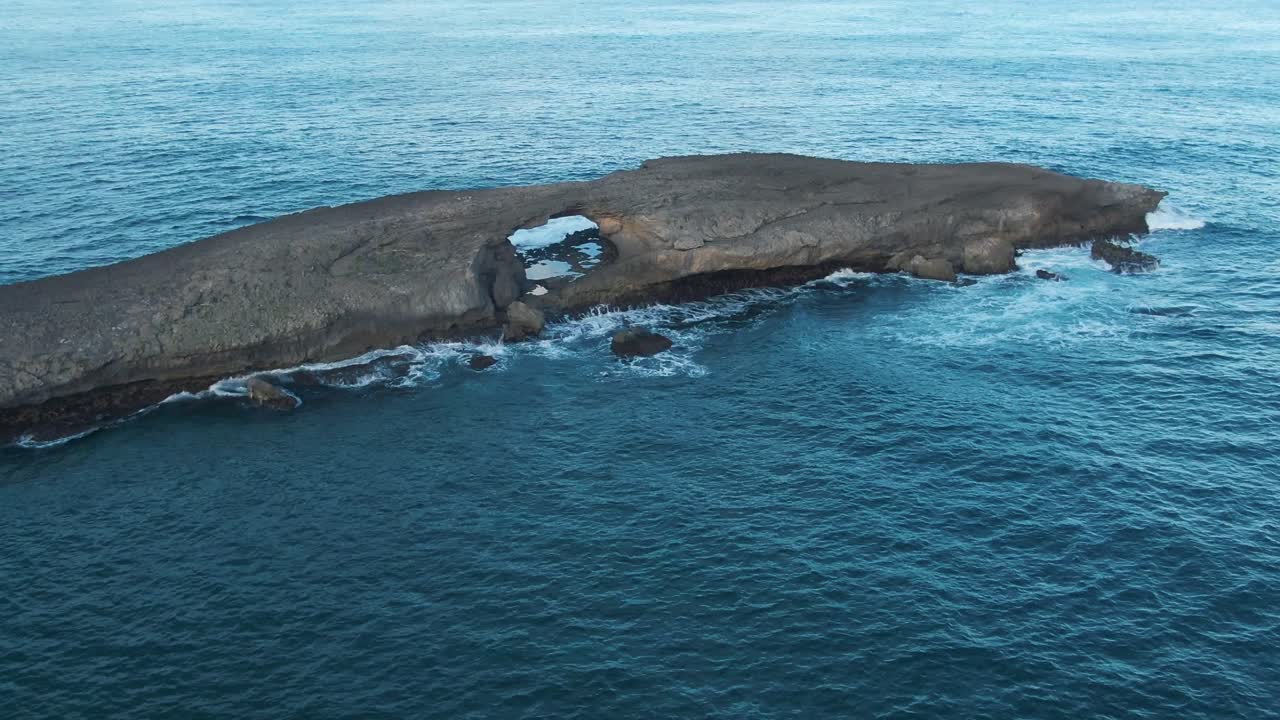 vista aérea de una roca en el medio del mar con un agujero en él