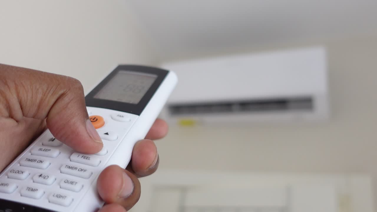 persona que utiliza el control remoto del aire acondicionado