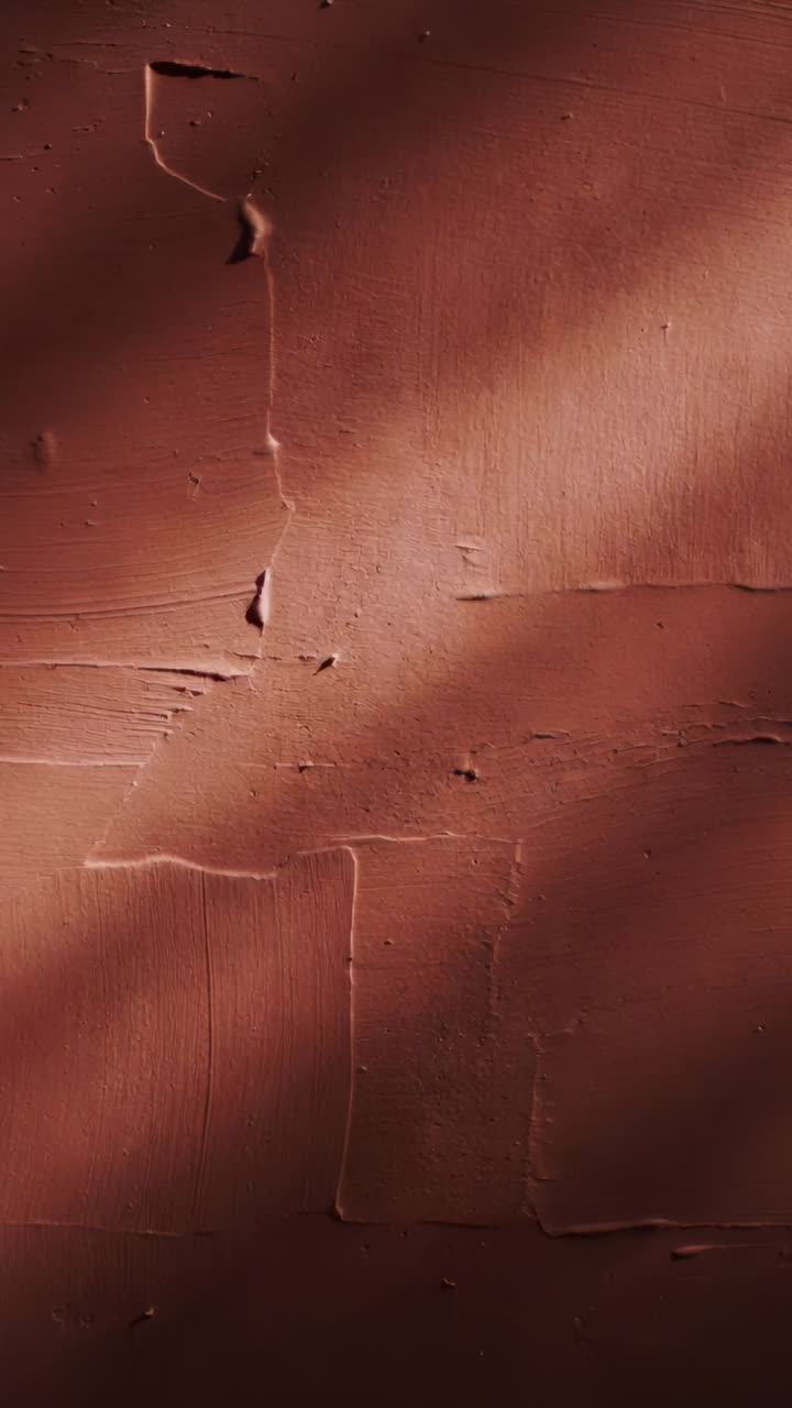 Video verticale: sole che si sposta proiettando un'ombra diagonale su una parete interna in gesso, mettendo in risalto i segni della cazzuola