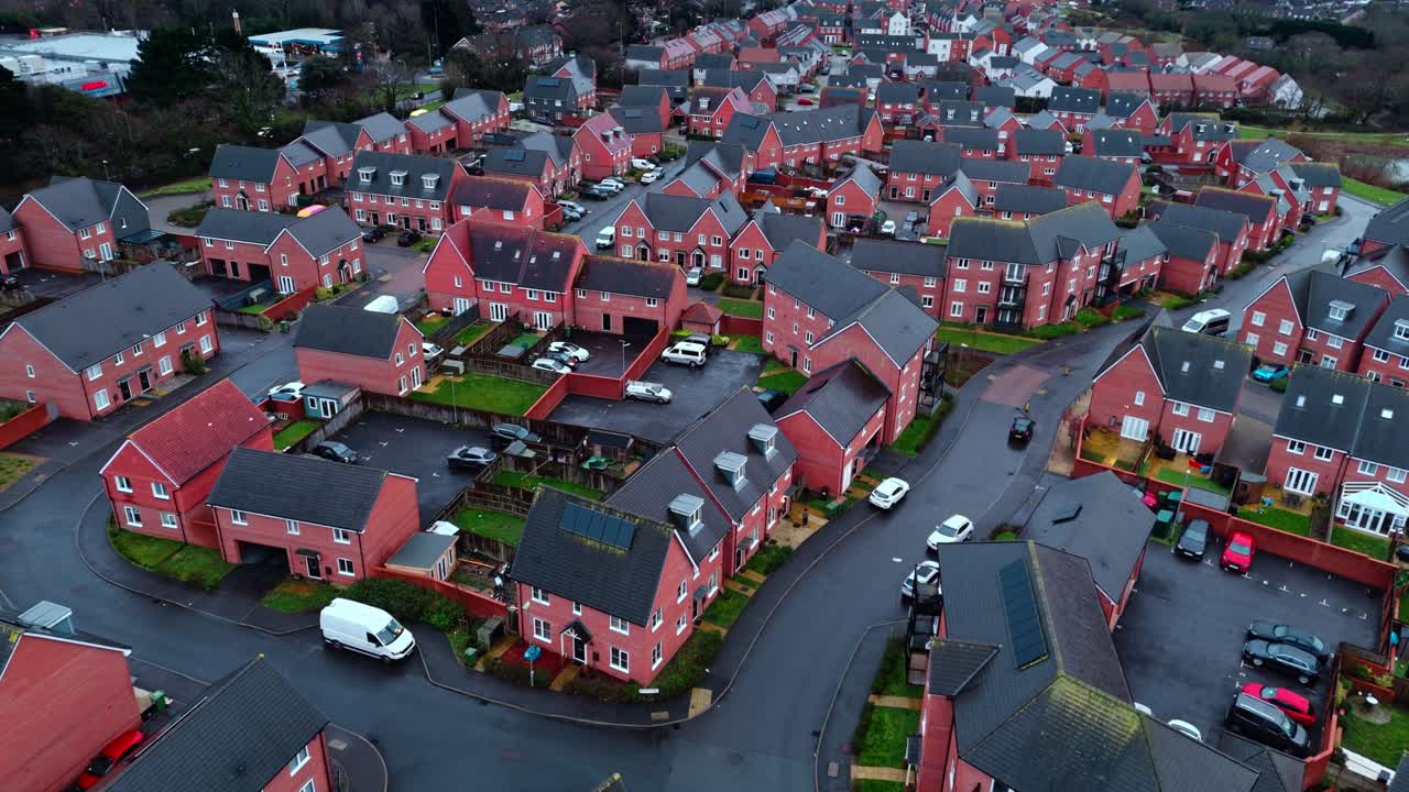 Luftoptagelser med drone over et lokalt engelsk forstadskvarter i det sydlige England ved tusmørke og solnedgang. Med befærdede veje og en rolig atmosfære med haver, træer og en dam