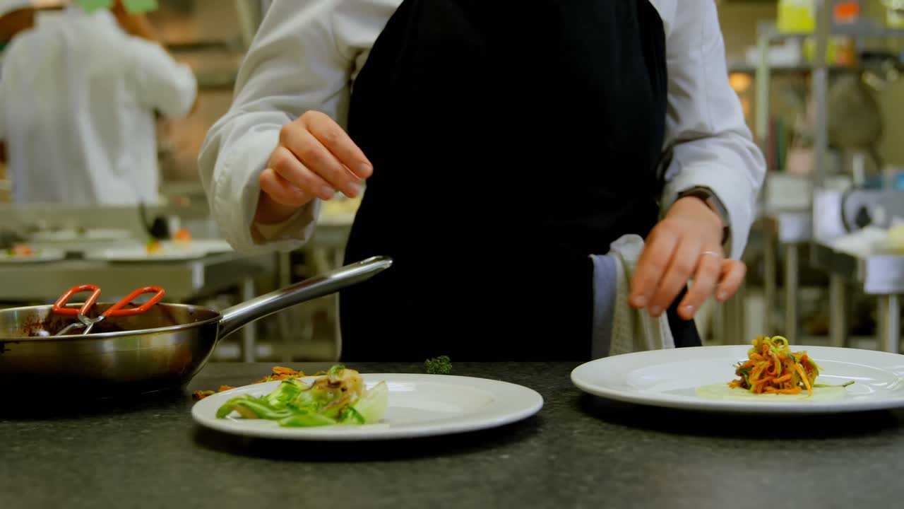 Cuoca che impiattisce il cibo in cucina 4k