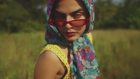 Beautiful-woman-vintage-style-fashion-red-glasses-stares-into-camera,-wilderness