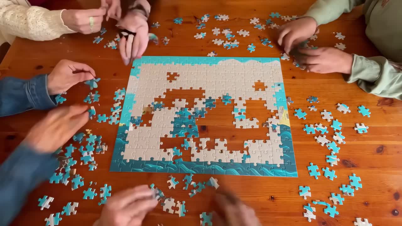 Ripresa video dall'alto di mani che assemblano un puzzle su un tavolo di legno, in stile lavoro di squadra.