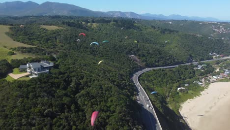 Drone-shot-of-Wilderness-beach-in-South-Africa---drone-is-towards-a-hill-full-of-paragliders