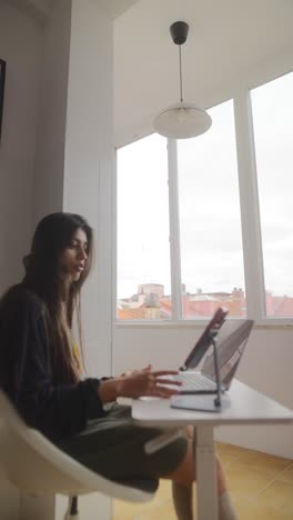 woman working from home at a laptop in front of a window