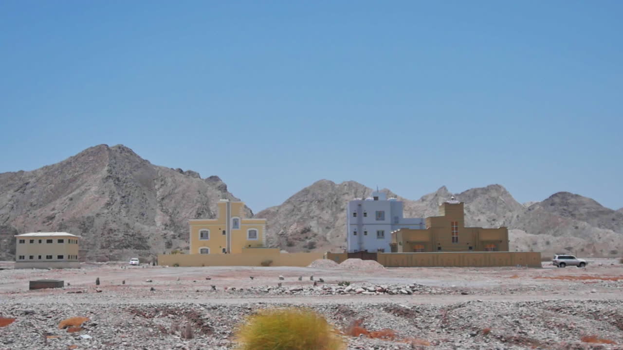 Case colorate nel deserto con sfondo montuoso sotto un cielo luminoso di mezzogiorno