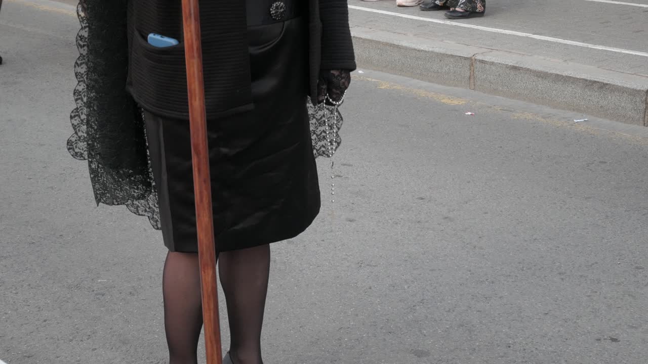 Alicante'deki Paskalya alayında siyahlar içinde, haç tutan bir kadın