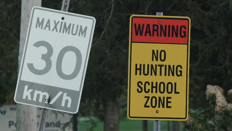 trees blowing behind a no hunting and speed limit sign