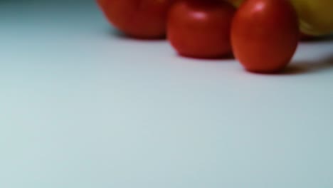 slow motion shot of a variety of tomatoes spilling, rolling and bouncing on a white surface