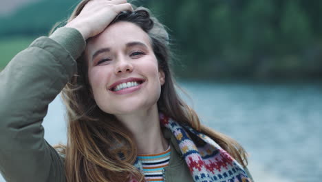 portrait happy young woman laughing having fun feeling excited playfully running hand through hair with wind blowing outdoors by lake 4k