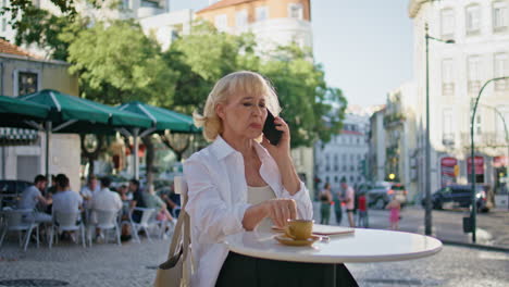 dissatisfied mature woman calling cellphone at street restaurant. elderly lady