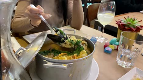 pretty woman serves big and amazing mussel with rice from a pot at the cascais market