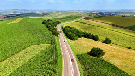 scenic highway through lush green fields. a winding highway cuts through vibrant green fields under a clear blue sky. trucks traverse the road