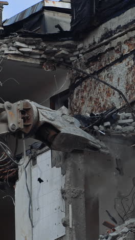 demolition of the house previously destroyed by natural disaster. special machinery breaks the parts of ruins. dusty debris falling down the ground. vertical video