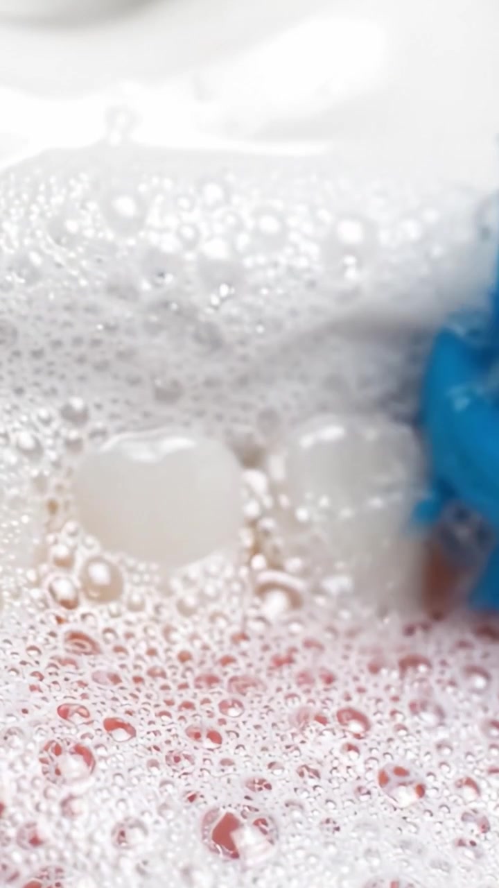 Uno sguardo ravvicinato a uno spazzolino in azione: bolle schiumose e setole vibranti illustrano l'importanza dell'igiene dentale e delle tecniche efficaci di pulizia dei denti.