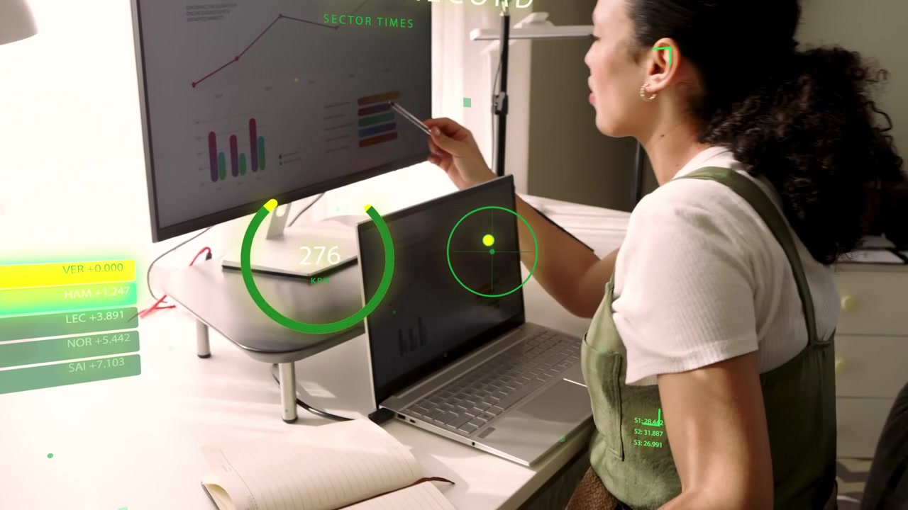 Monitor updating metrics with HUD overlays, woman pointing at graphs and writing notes for business