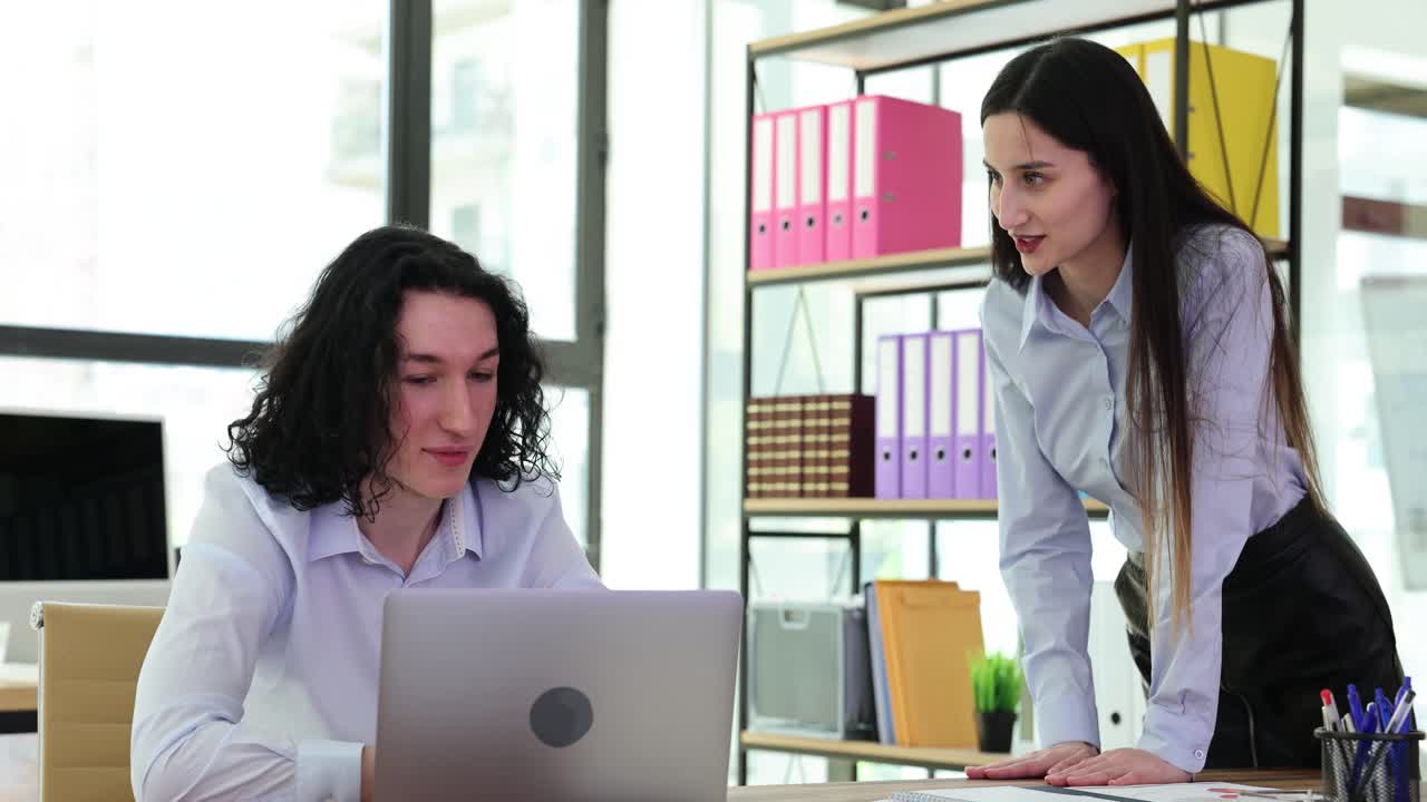 Two business people in office collaborating on a laptop