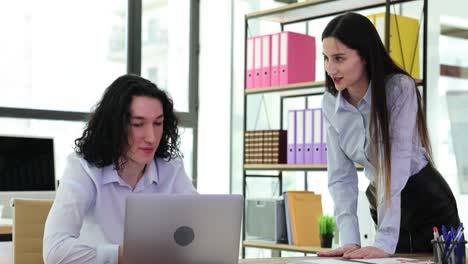 two business people in office collaborating on a laptop