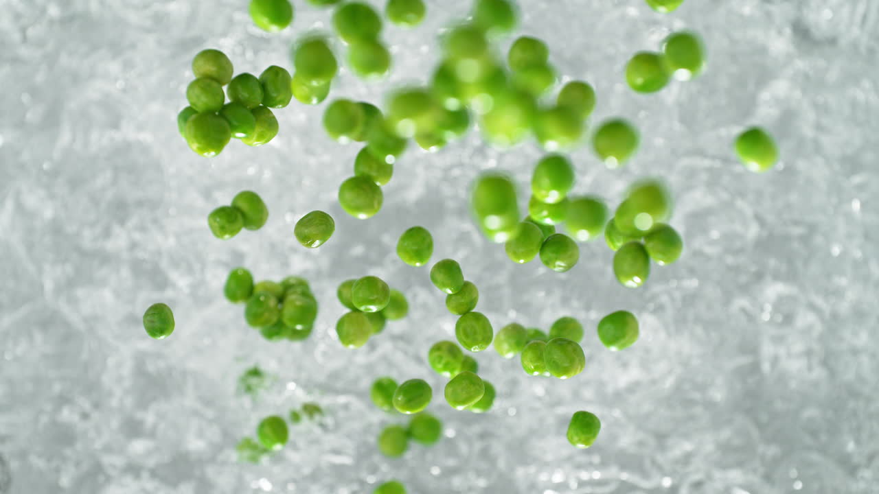 녹색 완두콩이 는 물의 비에 떨어지고 느린 동작으로 스플래시를 만들고, 테이블  뷰