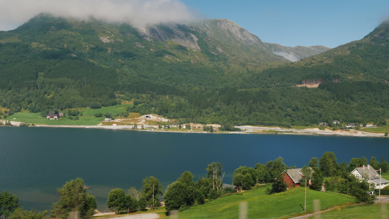 la orilla del fiordo la cima de las montañas se están ahogando en las nubes vista desde la ventana de t