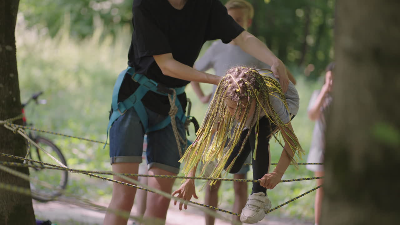 en el campamento de verano mi hija aprende a superar obstáculos de cuerda y escalada en roca. enseñar a los niños sobre turismo y senderismo