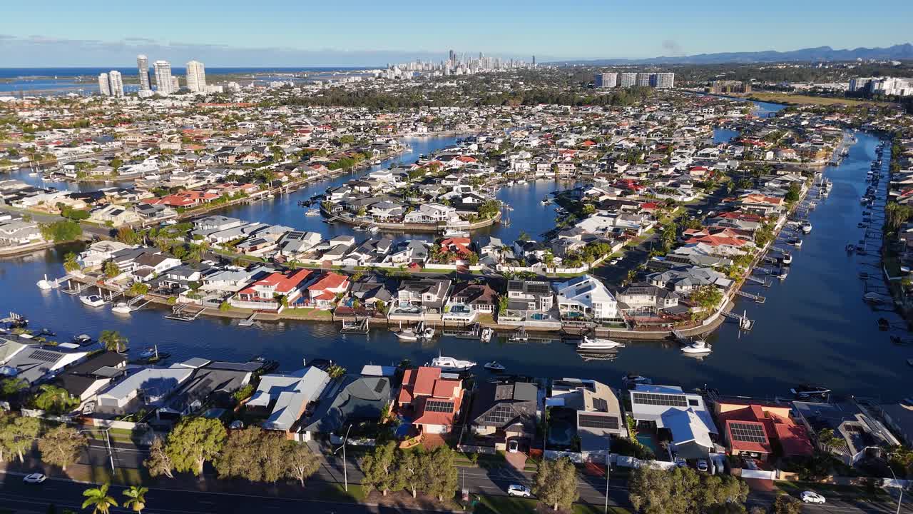 Drone footage captures luxurious homes and winding waterways under bright daylight in Gold Coast, Australia, showcasing urban and natural beauty