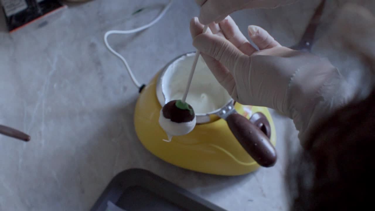 Ripresa dall'alto al rallentatore di una donna che posiziona un cake pop su un supporto decorativo