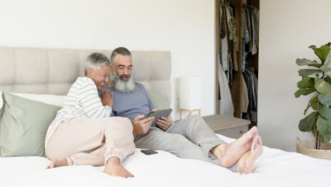 relaxing in bed, senior couple using tablet and smiling together