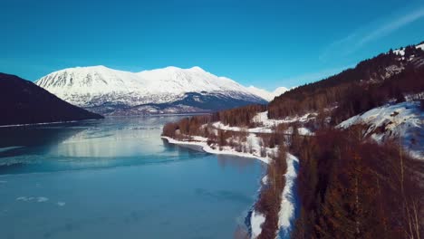 4k drone video of snow covered lakeside mountains in alaska during winter