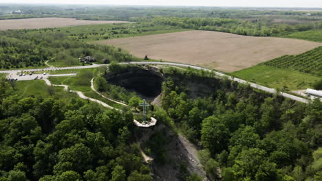 Aerial-drone-flight-over-famous-Devil's-Punch-Bowl-surrounded-by-countryside-at-sunlight