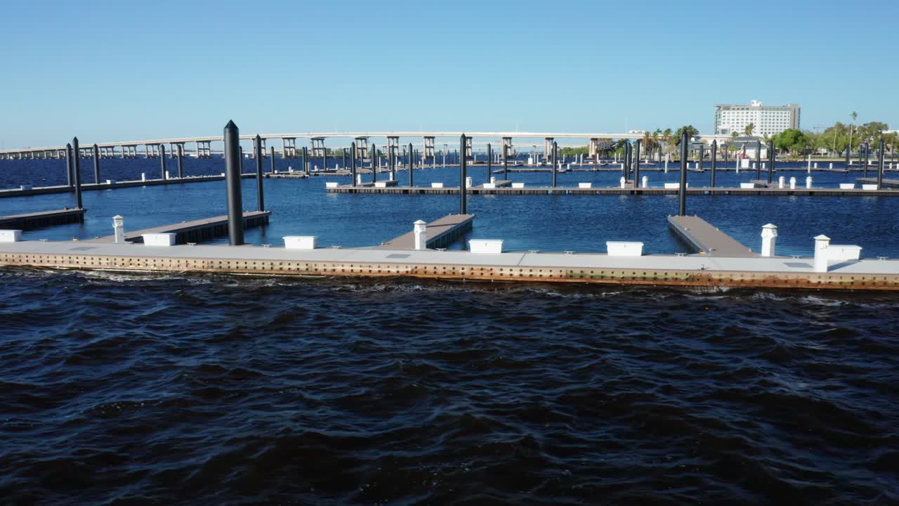 Un'ampia marina con pontili galleggianti si estende vuota sotto cieli sereni, con un ponte visibile in lontananza. Utile per progetti di pianificazione urbana o sviluppo del lungomare.