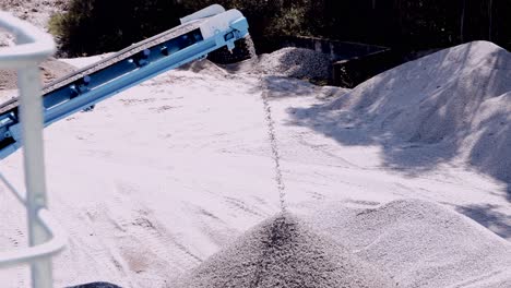 conveyor belt distributing crushed stone creating mounds in a mining quarry