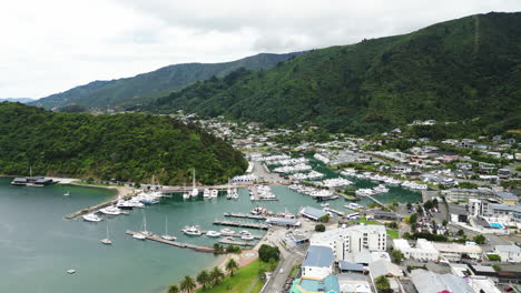 Cozy-tiny-town-of-Picton-with-pier-and-boats-in-New-Zealand,-aerial-drone-view