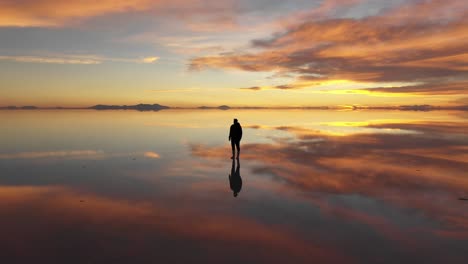 Silhouette-Eines-Mannes-Im-Salzsee-Salar-De-Uyuni-Während-Des-Sonnenuntergangs,-Orbitaler-360-Grad-Drohnenschuss,-Dunkelheitsdämmerung