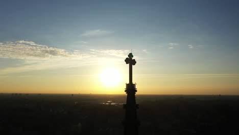 an aerial shot of a cathedral's steeple with a cross on top, taken at sunrise