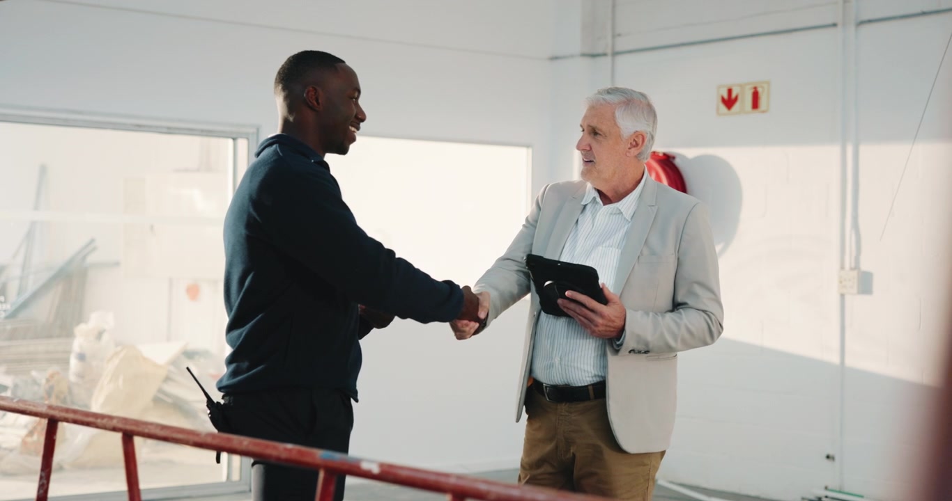 Two Men Shaking Hands in an Industrial Warehouse Setting