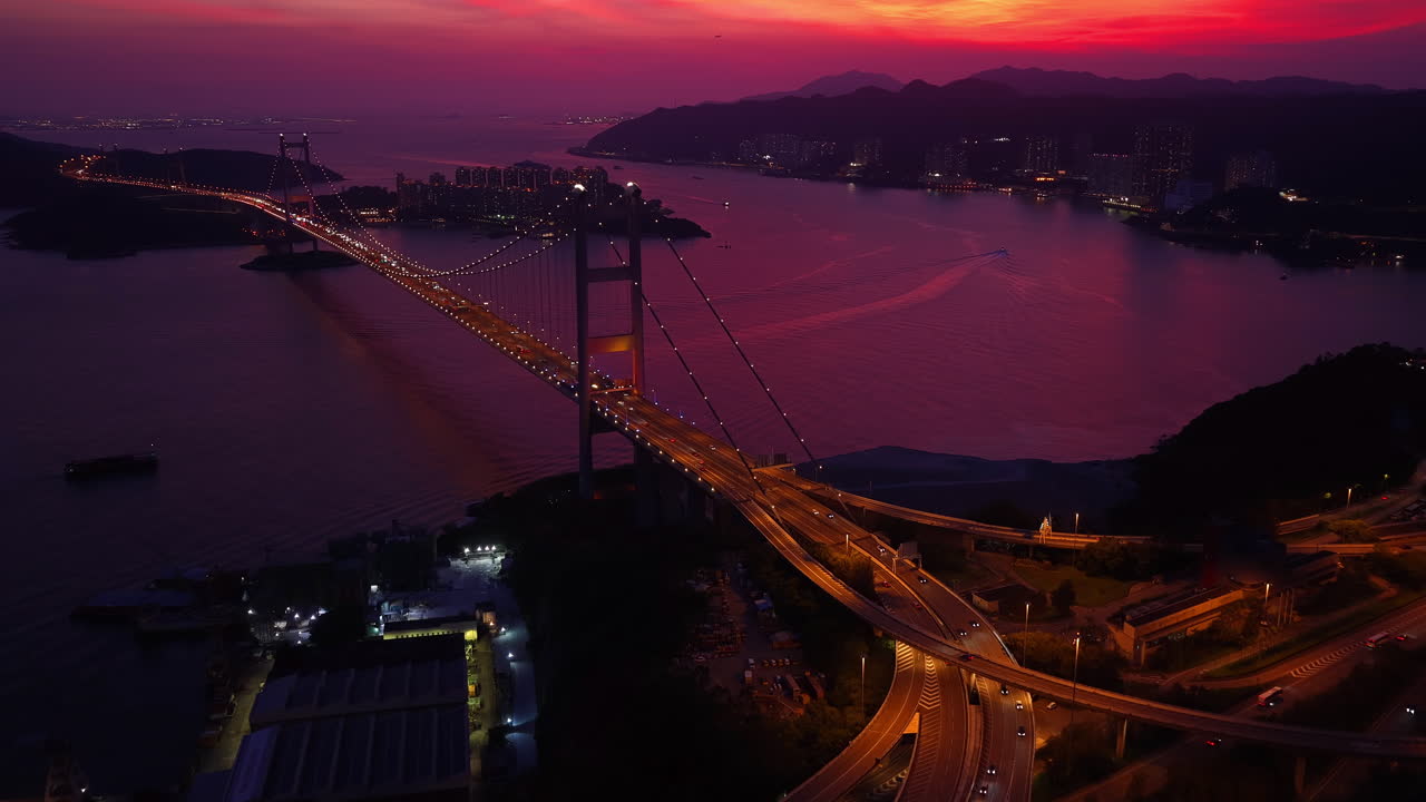 Cinematic aerial view of Tsing Ma Bridge in Hong Kong glowing at sunset, with winding roads, calm waters, and a vivid sky—capturing the essence of scenic travel and urban beauty