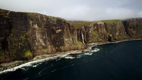 impresionantes cascadas se vierten en el océano desde acantilados verdes cubiertos de musgo, skye, escocia