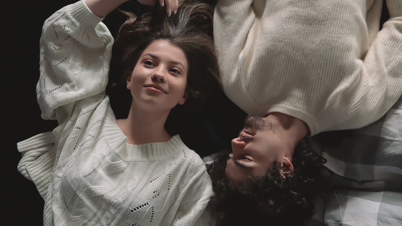 joven pareja romántica acostada en la cama con ropa de invierno