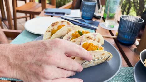 person grabbing fish taco at outdoor resort restaurant dining table