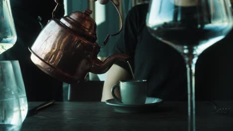 tea being poured from copper teapot, close up