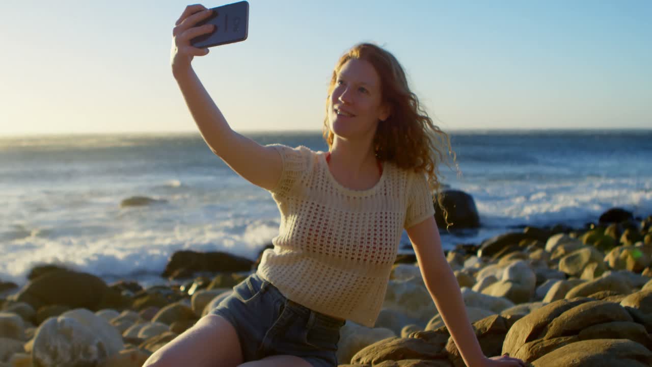mujer tomando una selfie con teléfono móvil en la playa 4k