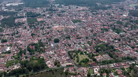 Aerial-hyperlapse-flying-over-and-mountain-to-see-downtown-historic-Antigua,-Guatemala