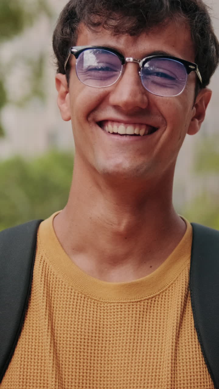 Portrait of European young man, cute geeky male studet smiling outdoors with