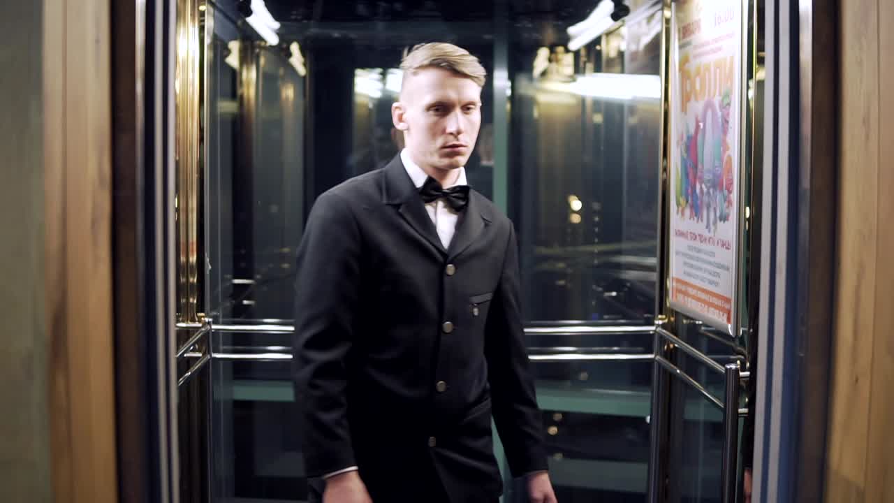 검은색 의상을 입은 젊은 사업가와 유리 문을 가진 엘리베이터